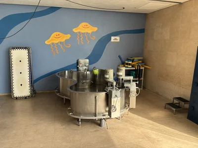 Industrial kitchen with circular stainless vats; blue wall features a yellow jellyfish mural.